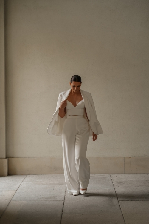 Braut im modernen weißen Jumpsuit mit Spaghettiträgern – elegante Wahl für eine Sommerhochzeit in Berlin