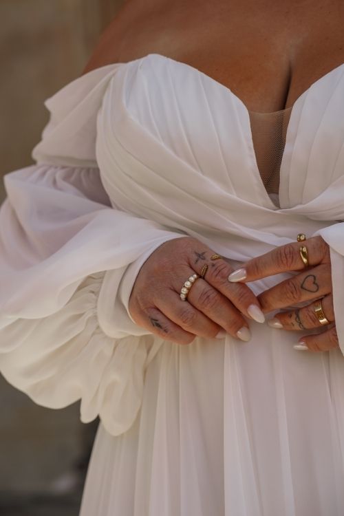 Detailaufnahme eines Chiffon Brautkleids mit Off-Shoulder-Ärmeln und Schmuckringen – Curvy Brautmode in Berlin und Brandenburg
