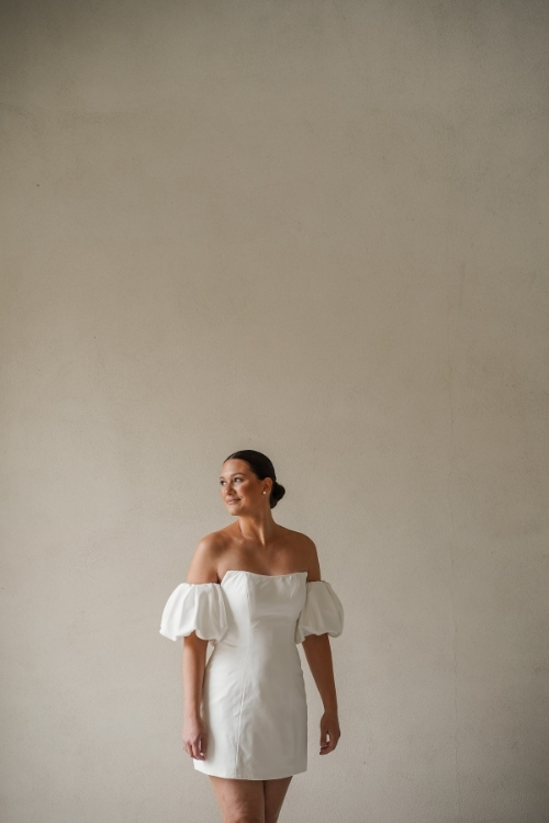 Braut in kurzem weißen Kleid mit Puffärmeln im Off-Shoulder-Stil – ideal für eine Sommerhochzeit